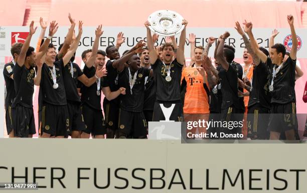 Leon Goretzka of FC Bayern Muenchen lifts the German Championship trophy surrounded by the team after the season's last Bundesliga match between FC...