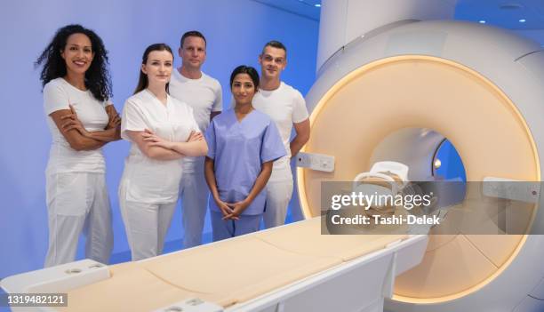 diverso equipo de científicos médicos posando con los brazos cruzados en la sala de resonancia magnética de alta tecnología - mri technician fotografías e imágenes de stock