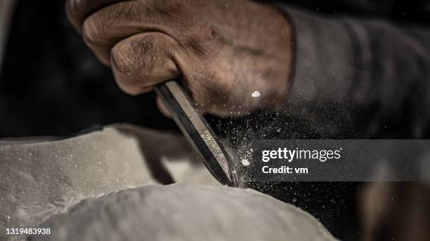 primo passo della mano di uno scultore mentre scalpella una pietra - scultura foto e immagini stock