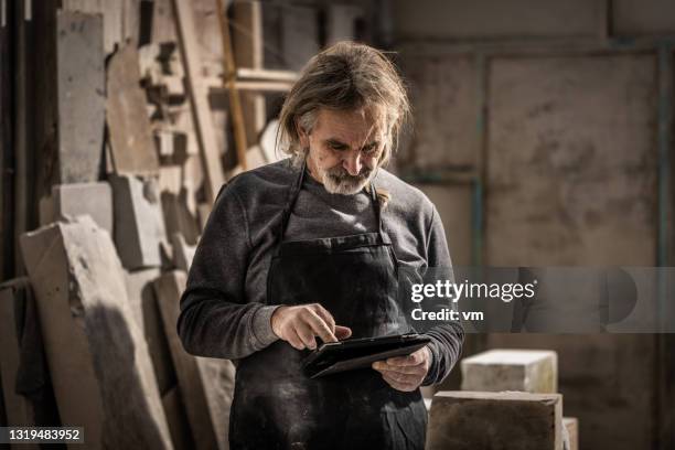sculptor in his studio using a digital tablet - stone tablets stock pictures, royalty-free photos & images