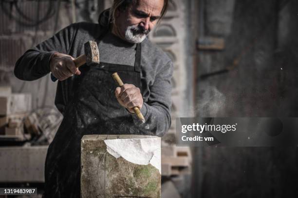 sculptor using hammer and chisel on a piece of stone - stone sculptor stock pictures, royalty-free photos & images