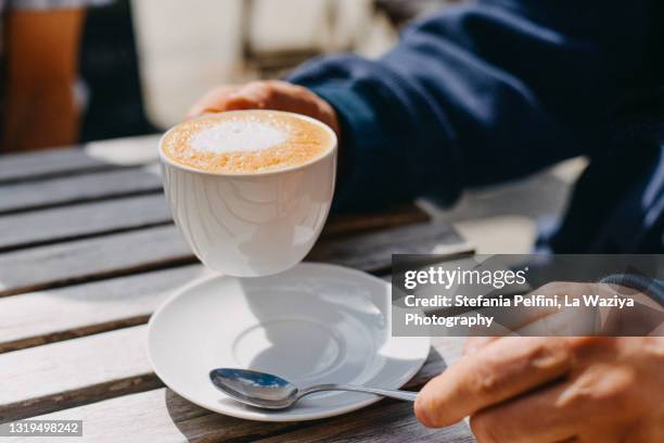 man's hand holding a vegan cappuccino - espresso trinken stock-fotos und bilder