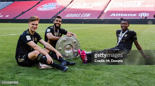 Joshua Kimmich, Eric Maxim Choupo-Moting and David Alaba of FC Bayern Muenchen smile holding the German Championship trophy after the season's last...