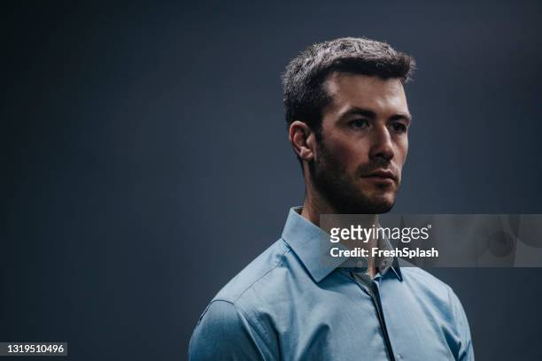 retrato de um belo jovem empresário de pé contra fundo cinza escuro (studio shot) - camisa cinzenta - fotografias e filmes do acervo