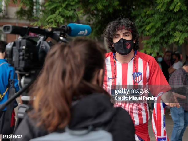 An Atlético de Madrid fan is interviewed by Spanish TV media while fans celebrate Atlético de Madrid winning La Liga at Neptuno Square on May 22 in...