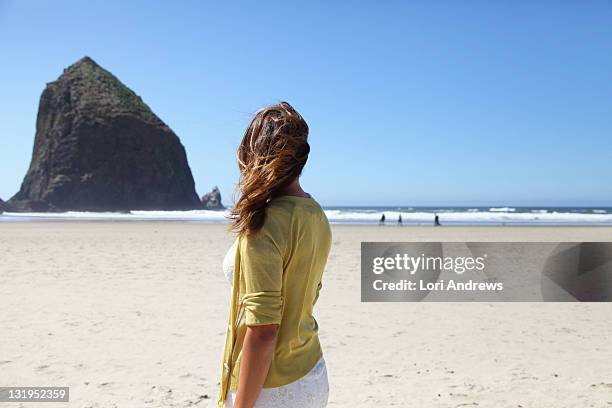 woman looks away on beach - cannon beach foto e immagini stock