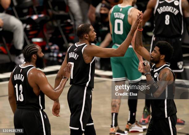 Kyrie Irving of the Brooklyn Nets is congratulated by teammates Kevin Durant and James Harden after Irving drew the foul against the Boston Celtics...