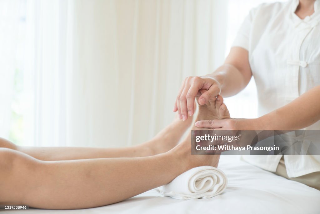 Woman having a pedicure treatment at a spa or beauty salon with the pedicurist massaging the soles of her feet with a pumice stone to cleanse dead skin and stimulate the tissue