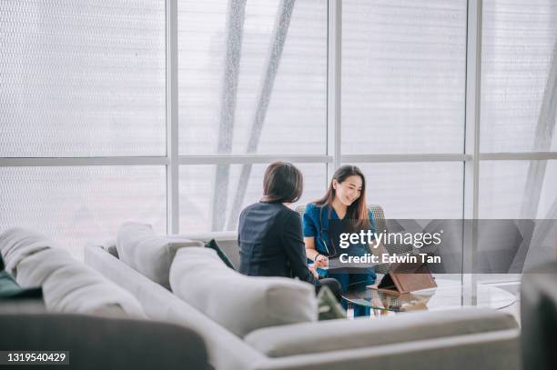 medico asiatico cinese che spiega il rapporto medico a una paziente donna nel suo divano dell'ufficio - image of patient foto e immagini stock