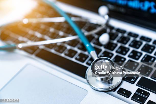 computer or data analysis - stethoscope over a laptop computer keyboard toned in blue - medizinisches-material stock-fotos und bilder