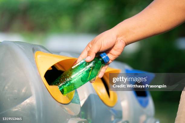 close up hand throwing empty plastic bottle into the trash - parklücke stock-fotos und bilder