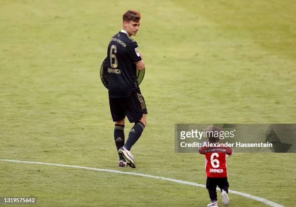 Joshua Kimmich of FC Bayern Muenchen celebrates with their son and the Bundesliga Meisterschale Trophy on pitch following the Bundesliga match...