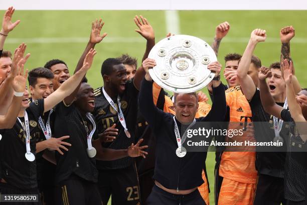 Hans-Dieter Flick, Manager of FC Bayern Muenchen lifts the Bundesliga Meisterschale Trophy in celebration with his players following the Bundesliga...