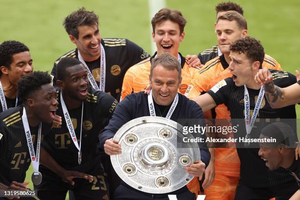Hans-Dieter Flick, Head coach of FC Bayern Muenchen lifts the Bundesliga Meisterschale Trophy in celebration with his players following the...