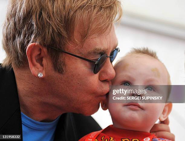 Rock legend Sir Elton John kisses little Lev, a patient of a specialized orphanage for HIV-positive children after the first results of the "Children...