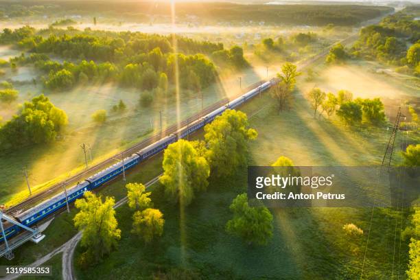 aerial view of passenger train on the railroad in misty dawn. railway passenger transportation - railroad stock-fotos und bilder