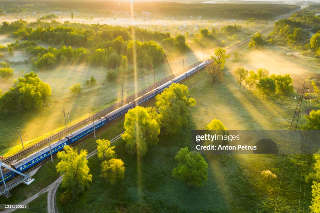 Aerial view of passenger train on the railroad in misty dawn. Railway passenger transportation