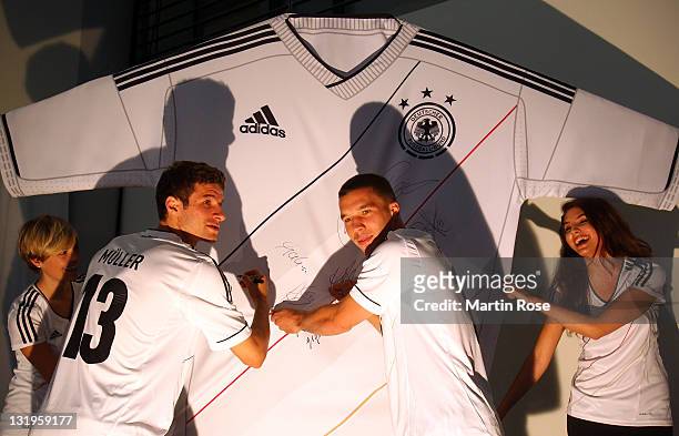 Thomas Mueller and Lukas Podolski signed autographs on a jersey model after the Germany national team Euro 2012 jersey launch at Mercedes Benz Center...