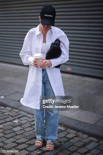 Michi Brandl wearing Agolde blue jeans, brown Balenciaga slides, white Zara crop top, white Karo Kauer Label blouse, black Bottega Veneta bag and...