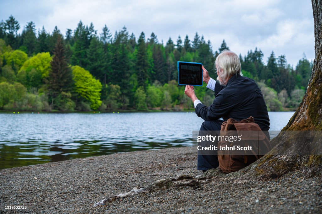 Senior man taking a photograph with a digital tablet