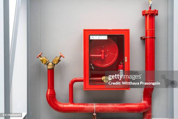 fire extinguisher and fire hose reel in hotel corridor - feuerwehrschlauch stock-fotos und bilder