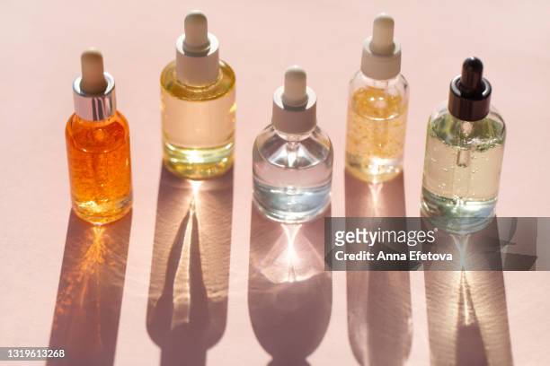transparent bottles of aromatic cosmetic products placed in row on pink background. trendy selfcare products of the year - aromatherapy oil stockfoto's en -beelden