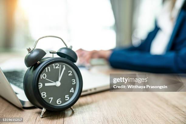 young businesswoman working on computer in office with alarm clock on desk - time card stock pictures, royalty-free photos & images