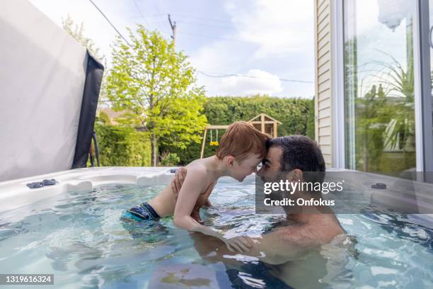 nette redhead kind und vater in der hot tub im hinterhof im sommer - family playing in backyard pool stock-fotos und bilder