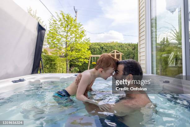 gosse et père mignons de rousse dans le bain à remous dans l’arrière-cour en été - bain à remous photos et images de collection