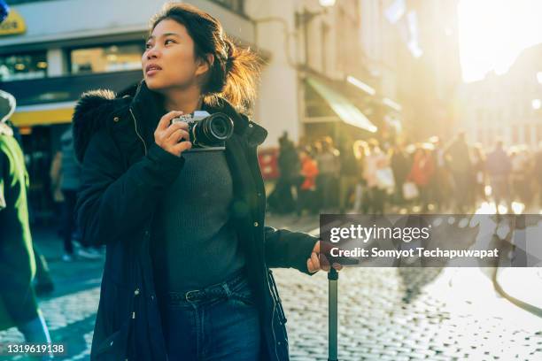 young asian female traveller walking sight seeing hand take photo with camera sunset at street downtown in brussels, belgium - brussels square stock pictures, royalty-free photos & images