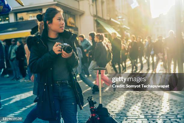young asian female traveller walking sight seeing hand take photo with camera sunset at street downtown in brussels, belgium - brussels square stock pictures, royalty-free photos & images