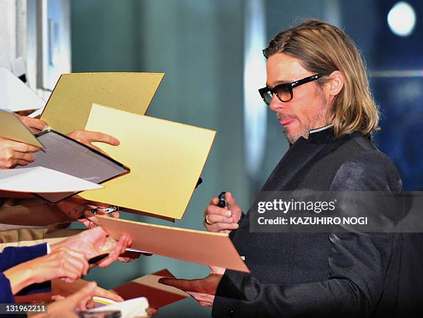 Actor Brad Pitt signs autographs for Japanese fans upon his arrival at the Japan premiere of his latest film "Moneyball' in Tokyo on November 9,...