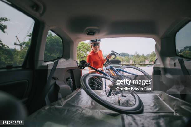 aziatische chinese vrouwen professionele fietser die haar fiets van de autoboomstam neerneemt klaar om te fietsen - train vehicle stockfoto's en -beelden