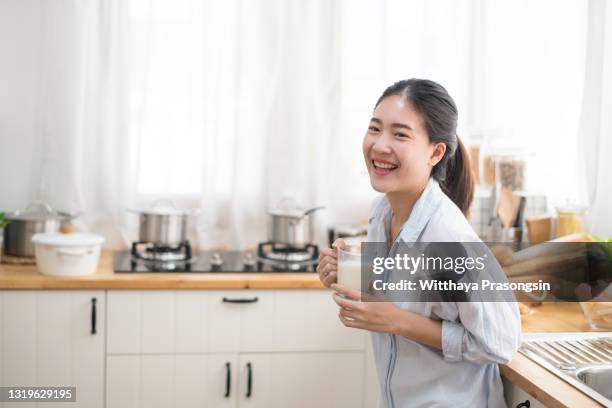 smiling young woman drinking milk - woman drinking milk stock pictures, royalty-free photos & images