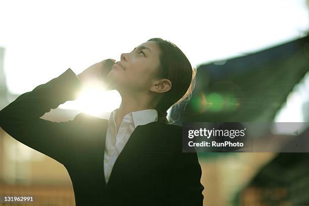 businesswoman talking on cell phone - japanese bussiness woman looking up stock-fotos und bilder