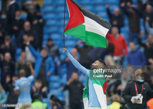 Riyad Mahrez of Manchester City wears the flag of Algeria, as he carries the flag of Palestine after Manchester City are presented with the Premier...