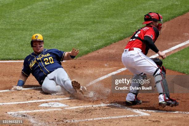 Daniel Vogelbach of the Milwaukee Brewers slides into home plate to score a run past Tucker Barnhart of the Cincinnati Reds in the first inning at...