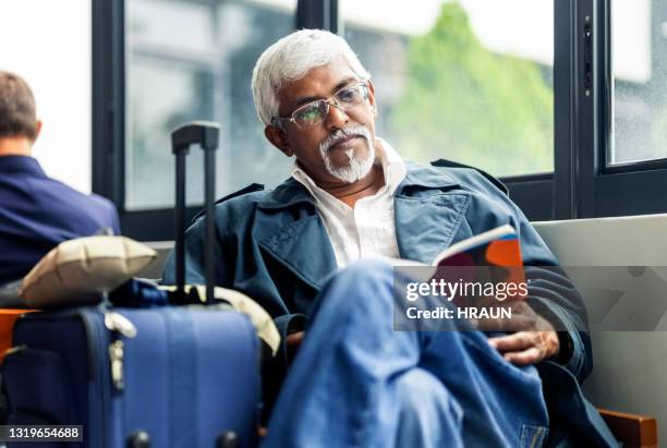 traveler waiting at airport lounge reading a book - indian ethnicity travel stock pictures, royalty-free photos & images