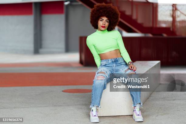 afro hairstyle woman sitting on bench - bauchfreies oberteil stock-fotos und bilder