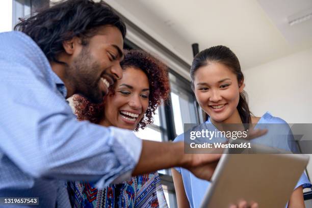 smiling young colleagues using digital tablet in university - international student day stock-fotos und bilder