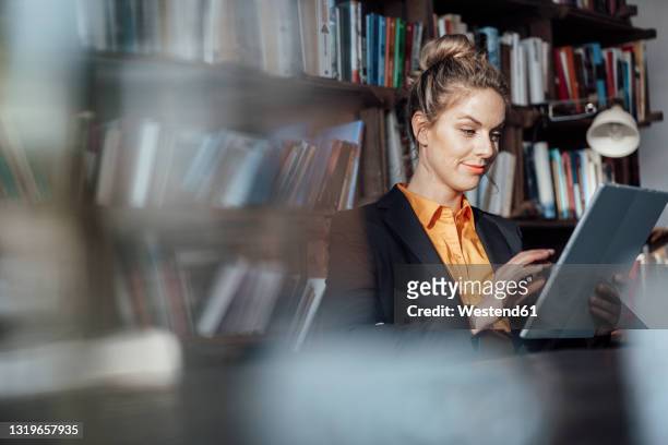 female mid adult entrepreneur using digital tablet in cafe - reflexo cabelo pintado imagens e fotografias de stock