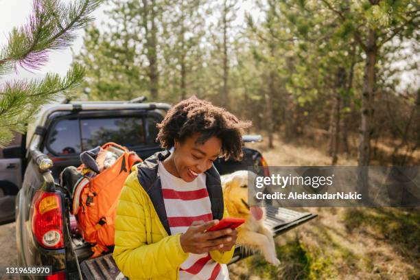 jonge vrouw die mobiele telefoon met behulp van terwijl op een roadtrip - car mobile stockfoto's en -beelden