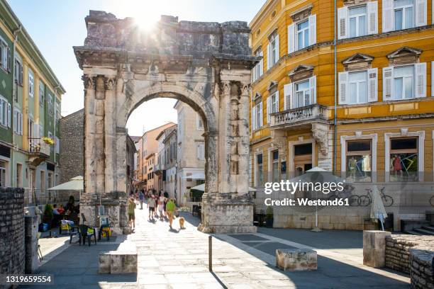 croatia, istria county, pula, sun shining over arch of sergii - pula croatia stock pictures, royalty-free photos & images