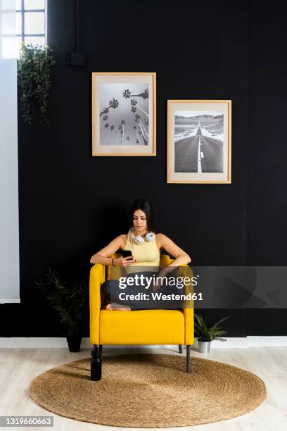 sportswoman using mobile phone while sitting at home - donna poltrona foto e immagini stock