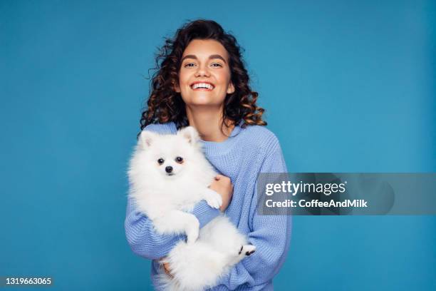 studio-porträt von lächelnden jungen frau hält kleinen hund - woman holding dog studio stock-fotos und bilder