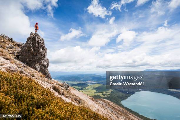 new zealand, tasman district, male hiker standing on top of rock formation overlooking sceniclake rotoiti - nelson stock pictures, royalty-free photos & images