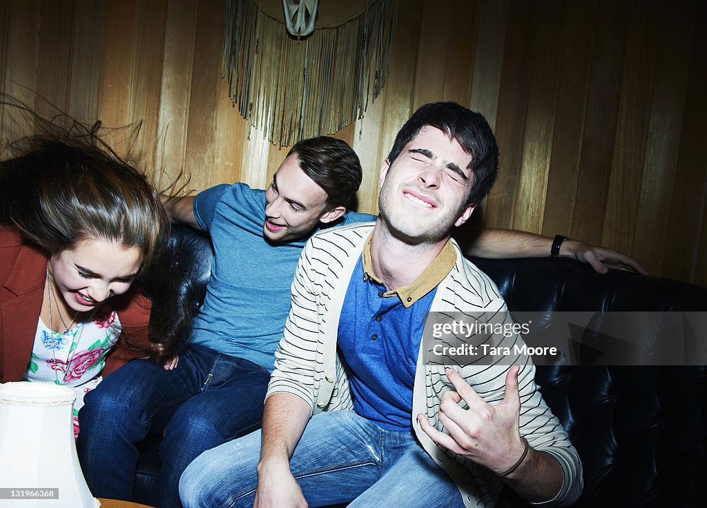 Group of three young adults doing air guitar