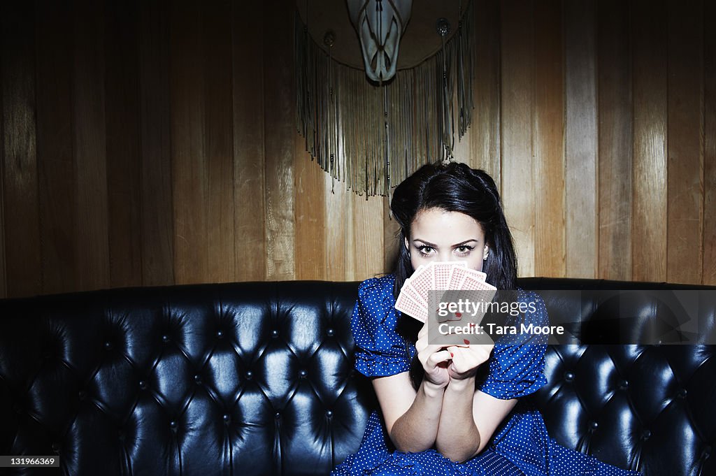 Young woman holding playing cards in front of face