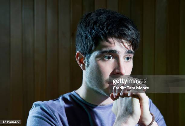 young man praying with an anxious expression - fear stock pictures, royalty-free photos & images