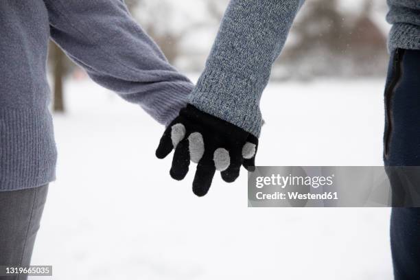 couple with gloves holding hands during winter - holding hands in the snow stock pictures, royalty-free photos & images